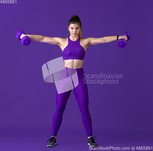 Image of Beautiful young female athlete practicing on purple studio background, monochrome portrait