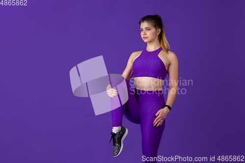 Image of Beautiful young female athlete practicing on purple studio background, monochrome portrait