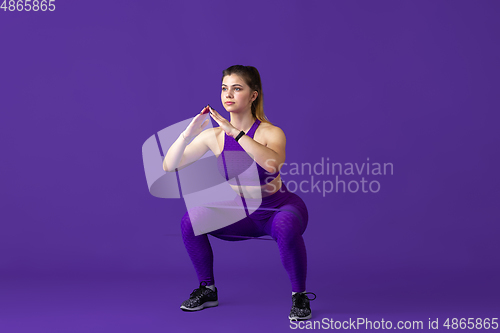 Image of Beautiful young female athlete practicing on purple studio background, monochrome portrait