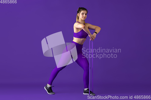 Image of Beautiful young female athlete practicing on purple studio background, monochrome portrait