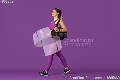 Image of Beautiful young female athlete practicing on purple studio background, monochrome portrait