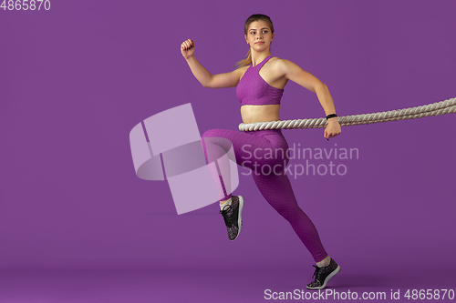 Image of Beautiful young female athlete practicing on purple studio background, monochrome portrait