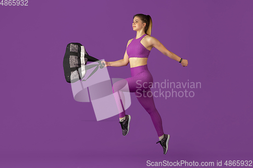 Image of Beautiful young female athlete practicing on purple studio background, monochrome portrait