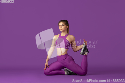 Image of Beautiful young female athlete practicing on purple studio background, monochrome portrait