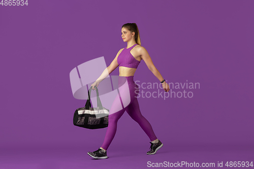 Image of Beautiful young female athlete practicing on purple studio background, monochrome portrait