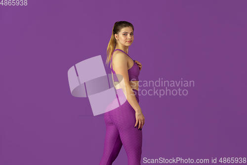 Image of Beautiful young female athlete practicing on purple studio background, monochrome portrait