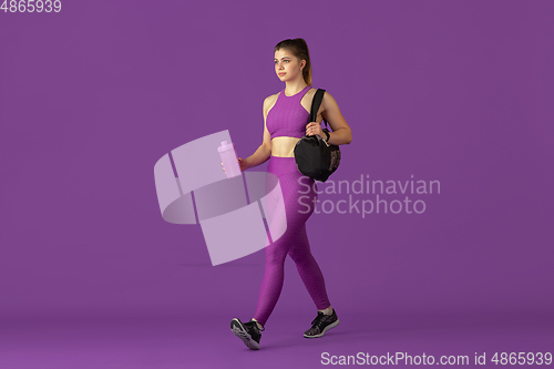 Image of Beautiful young female athlete practicing on purple studio background, monochrome portrait