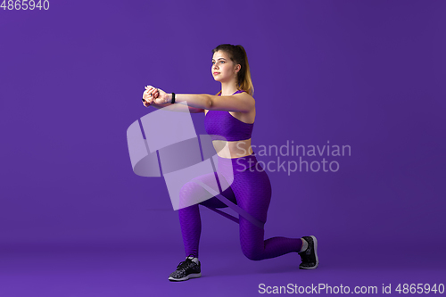 Image of Beautiful young female athlete practicing on purple studio background, monochrome portrait