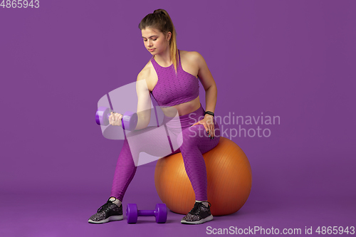 Image of Beautiful young female athlete practicing on purple studio background, monochrome portrait