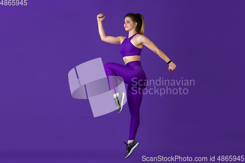 Image of Beautiful young female athlete practicing on purple studio background, monochrome portrait