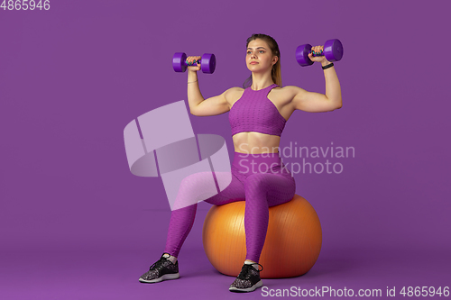 Image of Beautiful young female athlete practicing on purple studio background, monochrome portrait