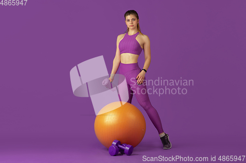 Image of Beautiful young female athlete practicing on purple studio background, monochrome portrait