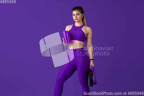 Image of Beautiful young female athlete practicing on purple studio background, monochrome portrait