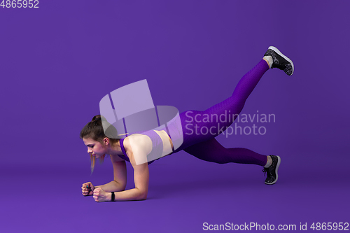 Image of Beautiful young female athlete practicing on purple studio background, monochrome portrait