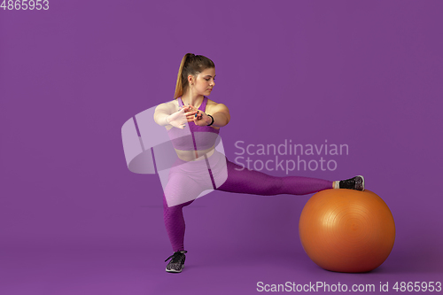 Image of Beautiful young female athlete practicing on purple studio background, monochrome portrait