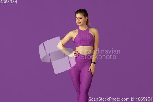 Image of Beautiful young female athlete practicing on purple studio background, monochrome portrait