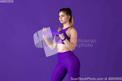 Image of Beautiful young female athlete practicing on purple studio background, monochrome portrait