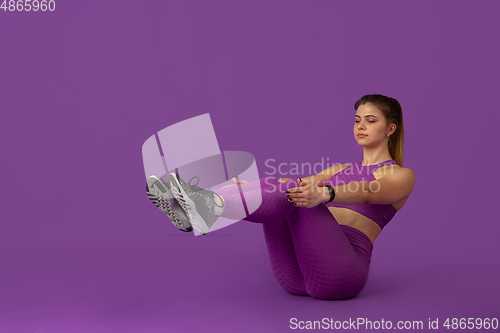 Image of Beautiful young female athlete practicing on purple studio background, monochrome portrait