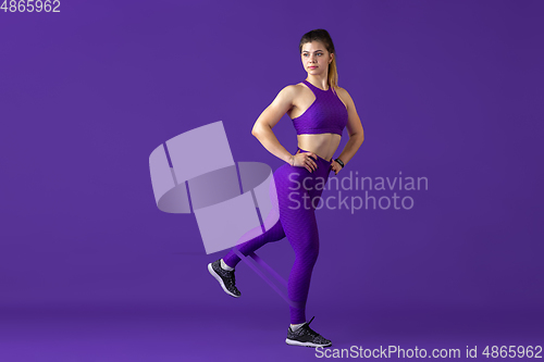 Image of Beautiful young female athlete practicing on purple studio background, monochrome portrait