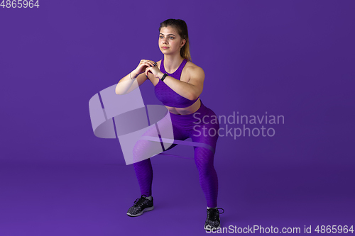 Image of Beautiful young female athlete practicing on purple studio background, monochrome portrait