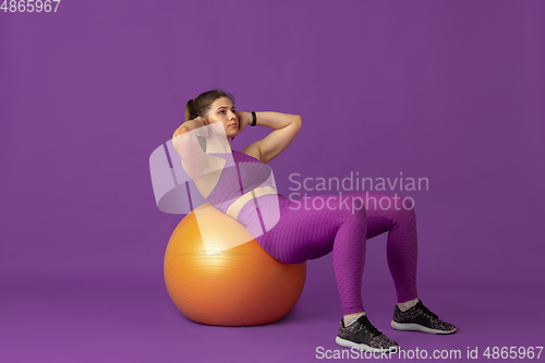 Image of Beautiful young female athlete practicing on purple studio background, monochrome portrait