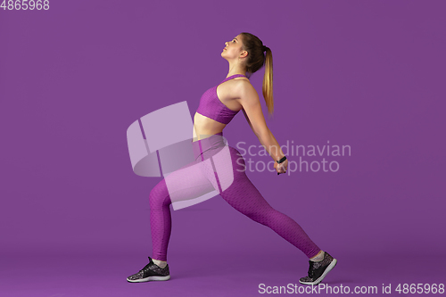 Image of Beautiful young female athlete practicing on purple studio background, monochrome portrait