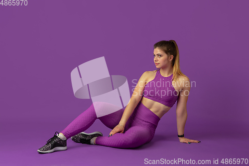 Image of Beautiful young female athlete practicing on purple studio background, monochrome portrait