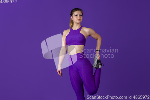 Image of Beautiful young female athlete practicing on purple studio background, monochrome portrait