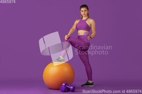 Image of Beautiful young female athlete practicing on purple studio background, monochrome portrait