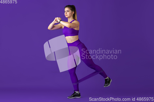 Image of Beautiful young female athlete practicing on purple studio background, monochrome portrait