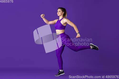 Image of Beautiful young female athlete practicing on purple studio background, monochrome portrait