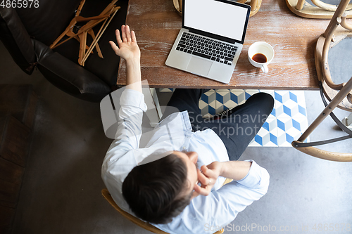 Image of Public institutions closed due to COVID-19 or Coronavirus outbreak lockdown, stressed owner of small business alone in his cafe, looking for solution, top view