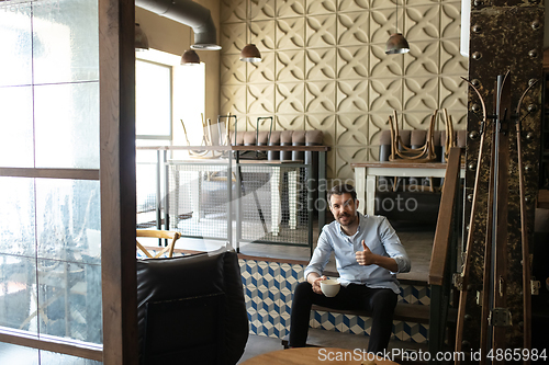 Image of Small business closed due to COVID-19 or Coronavirus outbreak lockdown, businessman alone in his restaurant, cafe, bar drinking coffee