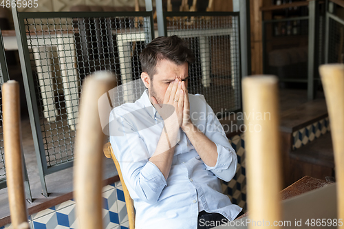 Image of Public institutions closed due to COVID-19 or Coronavirus outbreak lockdown, stressed owner of small business alone in his cafe, restaurant, bar, shocked and despair