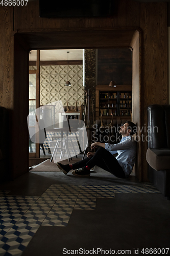 Image of Public institutions closed due to COVID-19 or Coronavirus outbreak lockdown, stressed owner of small business alone in his cafe, despair lying down the floor