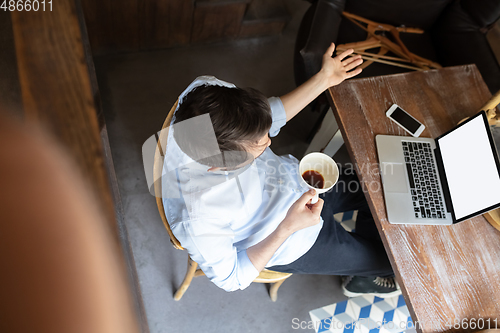 Image of Public institutions closed due to COVID-19 or Coronavirus outbreak lockdown, stressed owner of small business alone in his cafe, looking for solution, top view