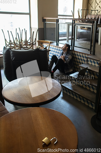 Image of Public institutions closed due to COVID-19 or Coronavirus outbreak lockdown, stressed owner of small business alone in his cafe, restaurant, bar