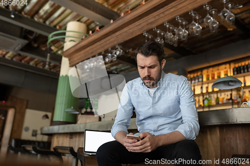 Image of Public institutions closed due to COVID-19 or Coronavirus outbreak lockdown, stressed owner of small business alone in his cafe, restaurant, bar