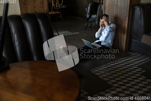 Image of Public institutions closed due to COVID-19 or Coronavirus outbreak lockdown, stressed owner of small business alone in his cafe, despair lying down the floor