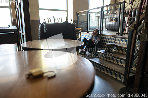 Image of Public institutions closed due to COVID-19 or Coronavirus outbreak lockdown, stressed owner of small business alone in his cafe, restaurant, bar