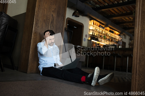 Image of Public institutions closed due to COVID-19 or Coronavirus outbreak lockdown, stressed owner of small business alone lying down the floor in his cafe, restaurant, bar