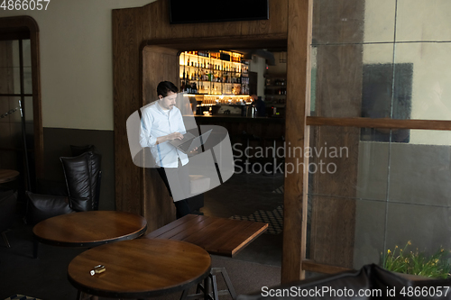 Image of Public institutions closed due to COVID-19 or Coronavirus outbreak lockdown, stressed owner of small business alone in his cafe, looking for solution