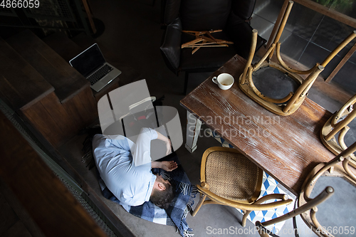 Image of Public institutions closed due to COVID-19 or Coronavirus outbreak lockdown, stressed owner of small business alone lying down the floor in his cafe, restaurant, bar