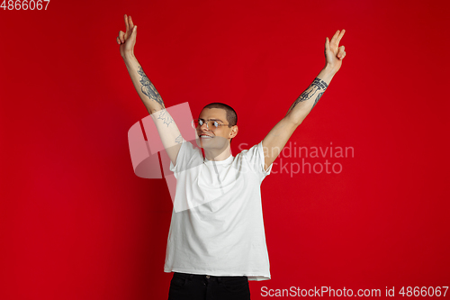 Image of Caucasian young man\'s portrait on red studio background, emotinal and expressive