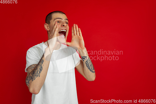 Image of Caucasian young man\'s portrait on red studio background, emotinal and expressive