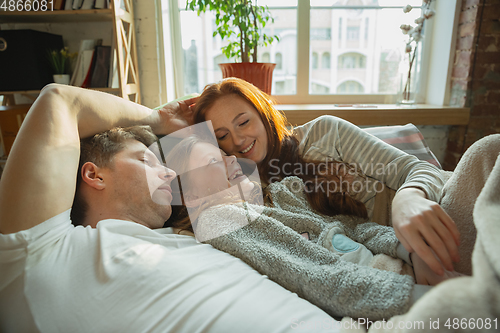 Image of Family spending nice time together at home, looks happy and cheerful, lying down together