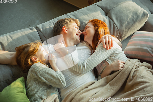 Image of Family spending nice time together at home, looks happy and cheerful, lying down together