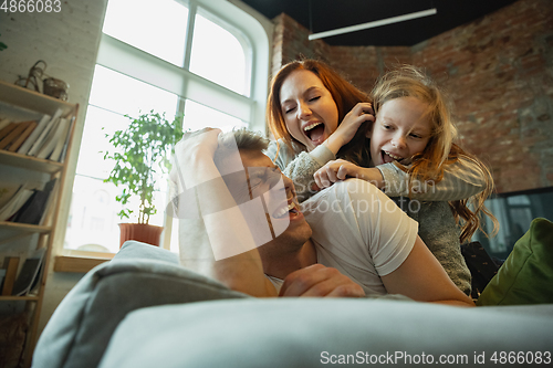 Image of Family spending nice time together at home, looks happy and cheerful, lying down together
