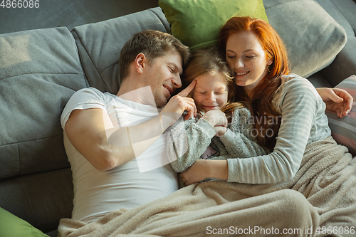 Image of Family spending nice time together at home, looks happy and cheerful, lying down together