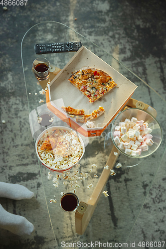 Image of Leftover pizza and popcorn on the table after family spending time together, watching cinema